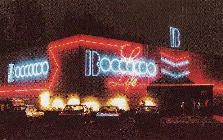 The Boccaccio Life club in Destelbergen at night: a low grey building with a red neon outline, the white-blue Boccaccio logo with red Life script, yellow spotlights and parked cars